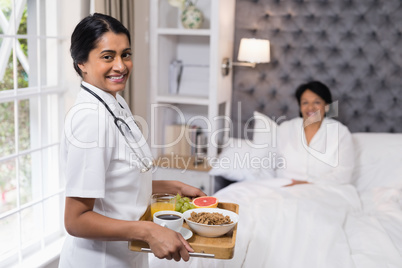 Portrait of nurse serving breakfast to patient at home
