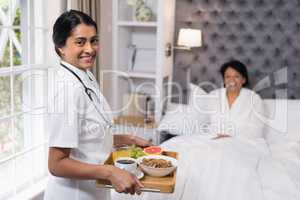 Portrait of nurse serving breakfast to patient at home