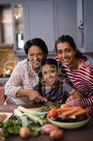 Portrait of smiling multi-generation family preparing food in kitchen