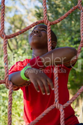 Happy boy leaning on net during obstacle course