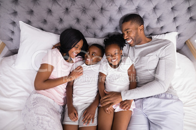 Smiling family lying together on bed at home
