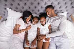 Smiling family lying together on bed at home