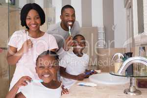 Happy family brushing teeth in bathroom at home