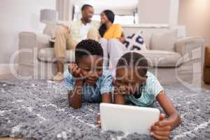 Children using digital tablet while parents siting on sofa at home
