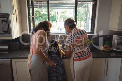 Little girl assisting mother and grandmother to wash utensil in kitchen