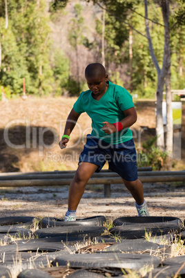 Boy running over tyres during obstacle course training