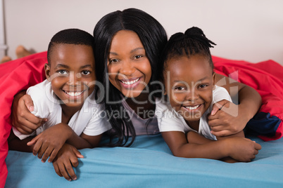 Portrait of smiling woman with children lying on bed