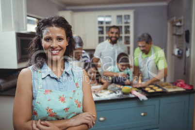 Woman smiling at camera while family members preparing dessert in background