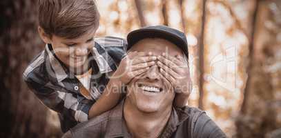 Boy covering fathers eyes in forest