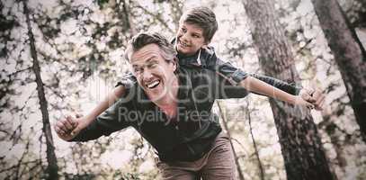 Cheerful father piggybacking son in forest