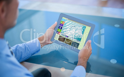 Composite image of businessman using his tablet