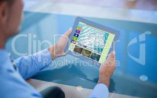 Composite image of businessman using his tablet