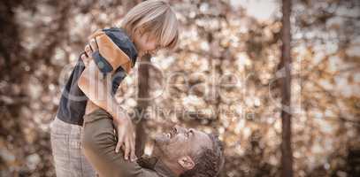 Playful father lifting up son in forest