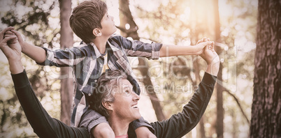 Father carrying son on shoulders while hiking in forest