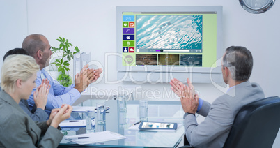 Composite image of business team applauding and looking at white screen