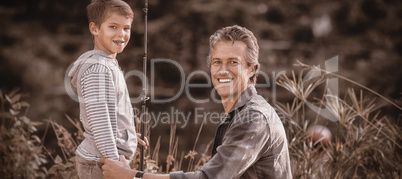 Father and son with fishing rod on field