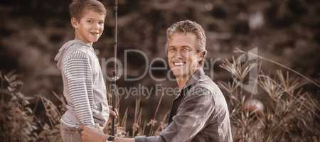 Father and son with fishing rod on field