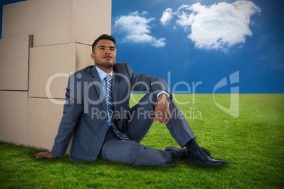 Composite image of businessman leaning on cardboard boxes against white background Composite image of businessman leaning on cardboard boxes against white background