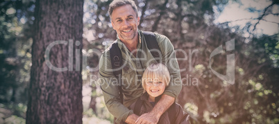 Happy father and son standing against trees in forest