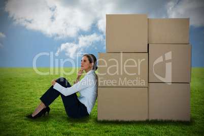 Composite image of businesswoman leaning on cardboard boxes against white background Composite image of businesswoman leaning on cardboard boxes against white background