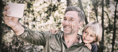Smiling father and son taking selfie in forest