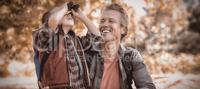 Father watching at boy looking through binoculars