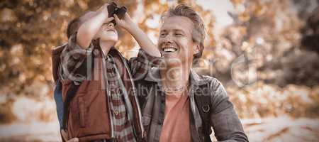 Father watching at boy looking through binoculars