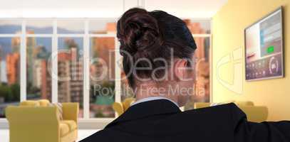 Composite image of rear view of businesswoman using digital screen