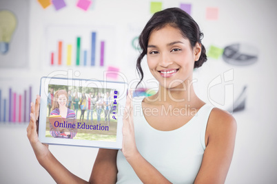 Composite image of happy businesswoman showing digital tablet in creative office
