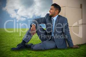 Composite image of businessman sitting near cardboard boxes against white background