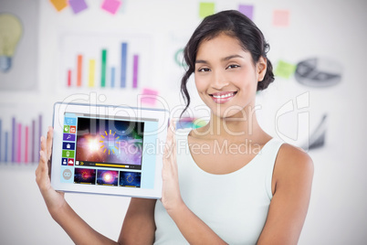 Composite image of happy businesswoman showing digital tablet in creative office