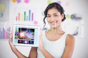 Composite image of happy businesswoman showing digital tablet in creative office