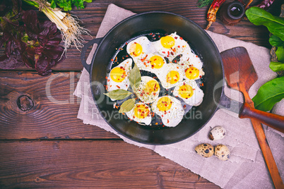 Fried quail eggs in a black cast-iron frying pan