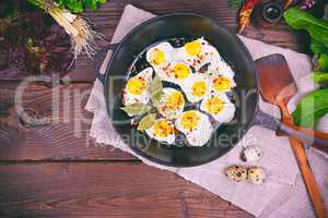 Fried quail eggs in a black cast-iron frying pan