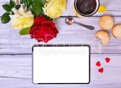 Tablet with white screen, cup of black coffee and bouquet of ros