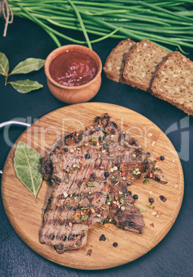 Fried on beef on a kitchen wooden board with fresh vegetables