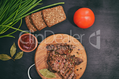 Grilled beef on a wooden board with fresh vegetables