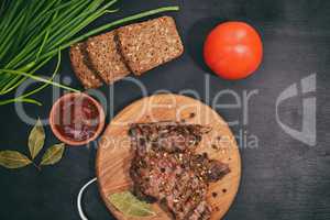 Grilled beef on a wooden board with fresh vegetables