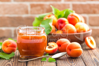 Apricot jam in a jar and fresh fruits with leaves