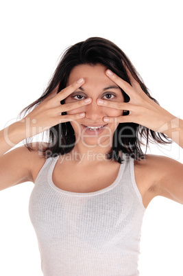 Young woman looking through her fingers.