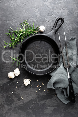 Empty cast iron frying pan on dark grey culinary background, view from above