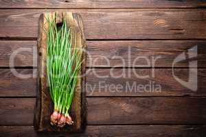 Green onion or scallion on wooden board, fresh spring chives