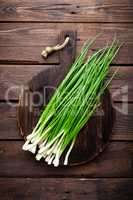 Green onion or scallion on wooden board, fresh spring chives