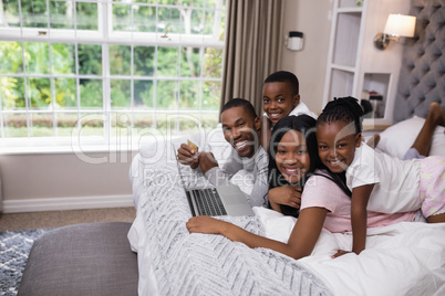 Portrait of smiling family shopping online on bed