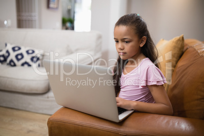 Girl using laptop while sitting on sofa