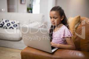 Girl using laptop while sitting on sofa