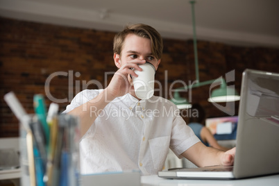 Male executive working on laptop while having coffee