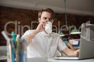 Male executive working on laptop while having coffee