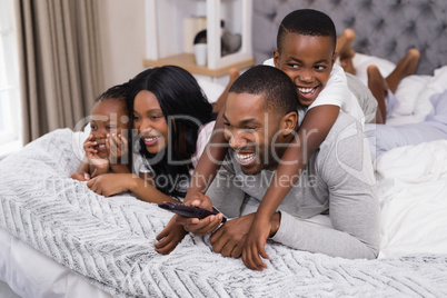 Happy family watching television while lying on bed