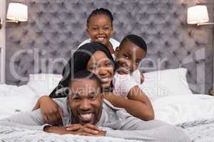 Portrait of smiling family lying on bed